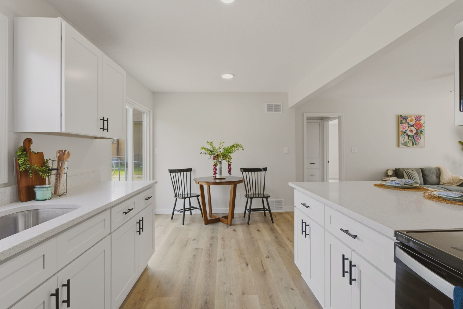 Renovated kitchen with white cabinets, quartz counters, and warm wood floors